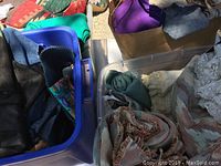 Four containers filled with various fabric pieces including upholstery and lace fabrics, mostly in darker and neutral colors.