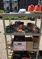 Wide view of shelves filled with various hardware and building supplies including gas cans, spray paint cans, electrical items, and small containers of nails and screws.