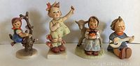 Lot of 4 vintage Goebel Hummel figurines arranged in a row showing full front view.