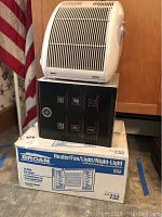 Sunbeam heater model 2587 88 on top of stacked boxes in corner.
