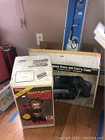 Two Coleman original boxes: one for electronic ignition lantern and carry case combo, other for electronic ignition two burner propane stove with carry case. Both boxes are upright showing product images and text.