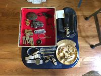 Overall shot of lot on black table showing decorative box, leather pouch, watches, pens, money clip and change dish.