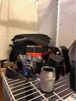 Wide shot showing camera body with attached lens, additional lens, leather pouch, instruction manual and carrying bag