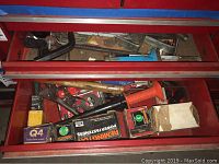 View of two red drawers filled with assorted hand tools, padlocks, power loads, and fasteners.