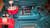 Makita cordless drill, two 18V rechargeable batteries, and charger laid inside a teal plastic case.