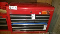 Red metal multi-drawer tool chest with labels and lock key visible