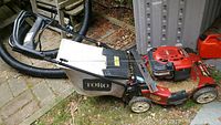 Side view of red Toro Recycler mower with attached grass bag and gas can beside it