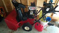 Full side view of red Toro Power Max snow blower showing housing, engine, wheels, handlebars and start cable.