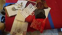 Overall view of rosary beads, pendants, and various cases and pouches arranged on a fabric surface.