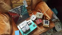 Lot displayed on brown leather chair including Revere Power Zoom 8mm movie camera in original box with four clocks.