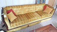 Front view of vintage sofa showing golden velveteen upholstery and carved wood frame