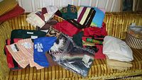 Overview of various textile items spread on a yellow sofa including multiple blankets, towels, travel bags, bed linens, and pillows.