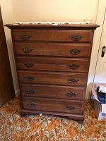 Front view of the 6 drawer wooden dresser showing medium-brown finish and decorative metal handles.