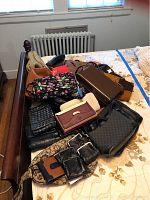 Assorted purses and wallets arranged on wooden bed frame, showing various colors, patterns, and materials including leather and fabric.
