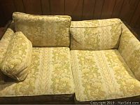 Front view of the yellow flowered love seat showing two seat cushions and two back cushions with floral patterned fabric upholstery.