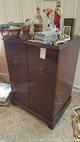 Front angle of vintage wooden TV cabinet showing two doors with round handles and dark wood finish.