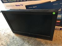 Westinghouse 26 inch flat panel HDTV with black frame and stand shown from front angle, screen off.