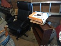 Black office chair, D Link boxed video phone, wood bookcase stacked with box on top, garage background