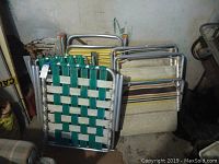 Stack of four vintage aluminum lawn chairs with various plastic fabric weaves and one chaise lounge.