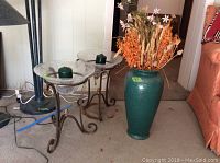 Photo showing 18 inch green ceramic W. Germany vase filled with dried flowers next to large wrought iron candle holders with green candles in crackle glass bowls.