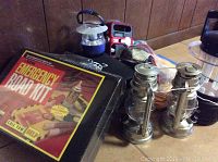 Photo showing two metal battery operated lanterns of silver-tone metal, approximately 10 inches tall