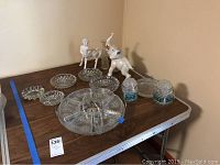 Table display of cut glass Lazy Susan, smaller cut glass bowls, ceramic elephant figurine, and two square ceramic jars