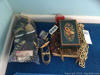 Photo showing assorted hair accessories in plastic bags, chain belts, zippered bag, and music box within a box