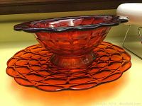 Cranberry glass bowl and matching platter photographed together on a surface showing texture and color.