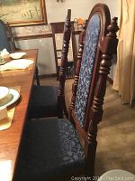 Close-up side view of two wooden dining chairs with upholstered blue patterned seats and backs.