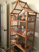 Full frontal view of the tall rattan shelf with items placed on shelves. Shows five tiers and the pagoda style roof