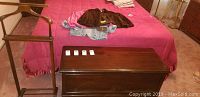 Wooden valet stand next to Lane cedar chest on carpeted floor in bedroom