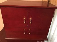 Front view of larger wooden jewelry cabinet closed