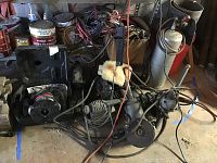 Power tools and accessories on floor in front of a metal shelf, including cords and a wool buffing pad visible.