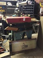 Craftsman table saw from side showing saw blade, metal body, wooden extension wings, and red Proto toolbox on top.
