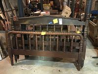 Full view of the Jenny Lind style wooden headboard showing turned spindle design and wheels on the legs.