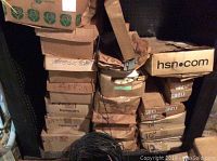 Stacked cardboard boxes containing candles in a basement setting.