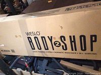 Box with Weslo Body2Shop branding, showing it as a cross training system with isokinetic resistance and 30+ exercises.
