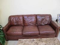 Full front view of three-seat brown leather sofa.