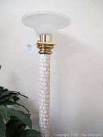 Full view of one floor lamp showing white crackle patterned base with gold accents and large white fluted glass shade.