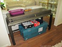 Front angled view of the black Asian inspired sofa table showing intricate crackle finish and brass latch detail.