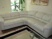 Front-wide view of three-piece off-white leather sectional sofa.