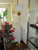 Two tall floor lamps beside white sofa and plant, showing overall height and style.