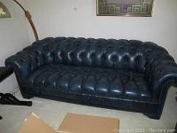 Front view of dark blue tufted leather sofa