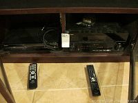 Pioneer VSX 01TXH stereo receiver with two remote controls placed in a wooden cabinet.