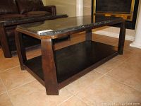 Side view showing dark wood legs and lower storage shelf of the coffee table