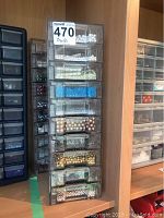 Stack of clear plastic storage drawers filled with a variety of white, blue, gold, pearl, and other colored beads.