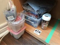 Four plastic containers with assorted beads in different colors and sizes arranged on a wooden shelf.