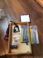 Wooden box containing Beadalon beading tools in packaging, black beading chain, and plastic spools
