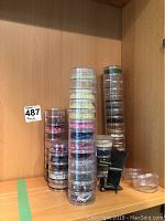 Stacks of clear plastic containers filled with beads in various colors such as yellow, pink, blue, and metallic tones.