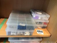 Five plastic compartment boxes stacked, containing mixed beads and jewelry supplies.